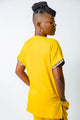 blouse médicale caribéenne jaune pour femme avec empiècements en madras roue brique, jaune moutarde et bleu -uniforme pofessionnel élégant et moderne twopikal wear avec dos uni.