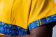 tunique médical homme jaune avec détails ethniques bleus, tenue professionnelle élégante twopikal wear , uniforme coloré caribéen infirmier ou aide soignante avec magnifique empiecement de motifs africains bleus.