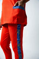 tunique médical femme rouge avec détails ethniques bleus, tenue professionnelle élégante twopikal wear , uniforme coloré caribéen infirmière ou aide soignante.