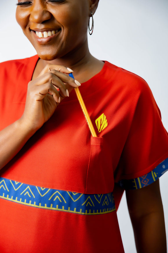 tunique médical femme rouge avec détails ethniques bleus, tenue professionnelle élégante twopikal wear , uniforme coloré caribéen infirmière ou aide soignante muni de poche stylo discrète.