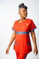 tunique médical femme rouge avec détails ethniques bleus, tenue professionnelle élégante twopikal wear , uniforme coloré caribéen infirmière ou aide soignante.